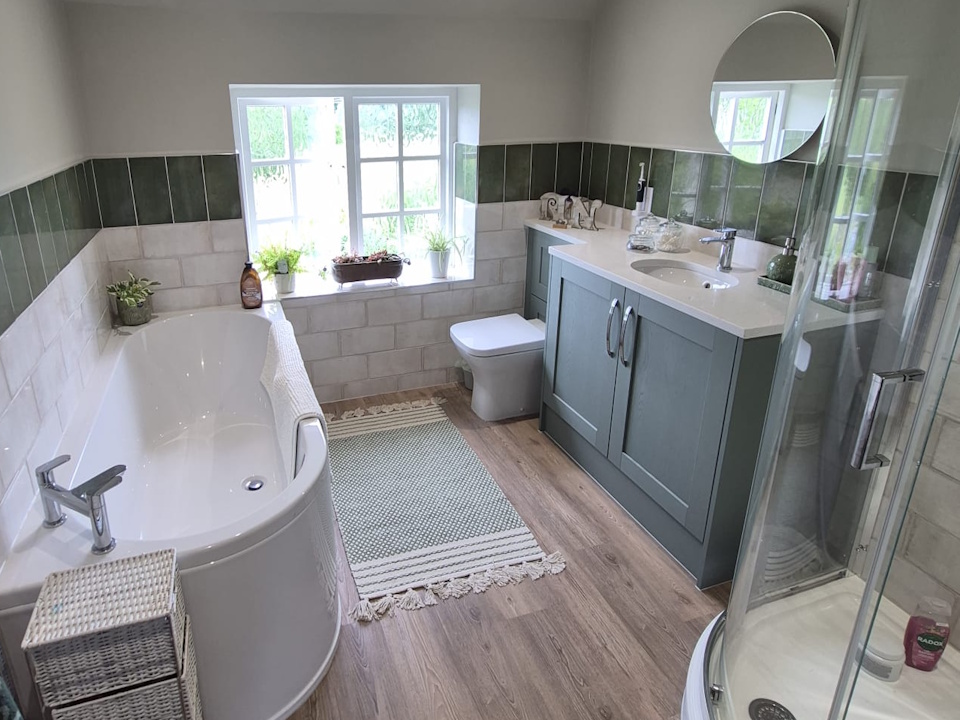 Family bathroom with curved bath, quadrant shower, sage green shaker vanity and green and white wall tiles