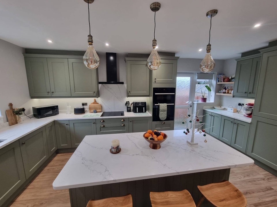 Sage green shaker kitchen with marble-effect quartz island and pendant lights
